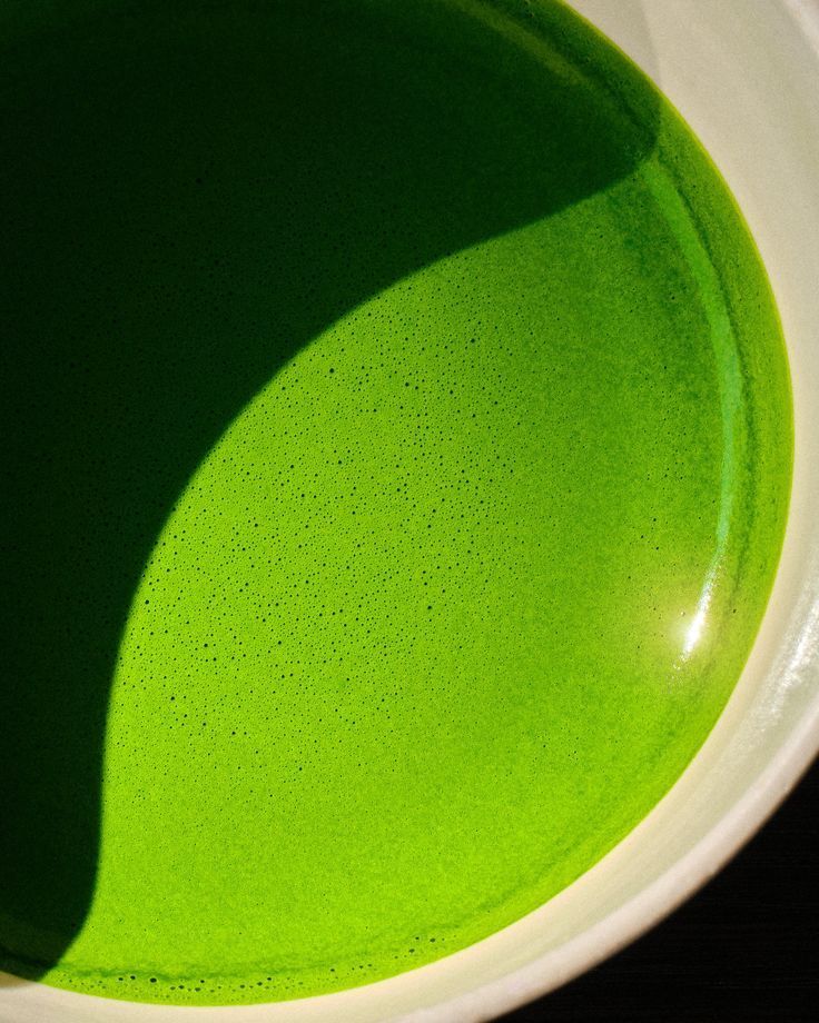 Close-up of vibrant green ceremonial matcha tea with fine froth in a white bowl