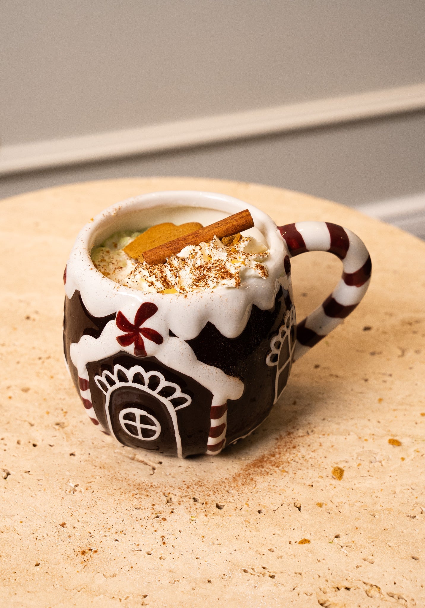 Festive mug of matcha latte with whipped cream, cinnamon stick, and cookie on a table