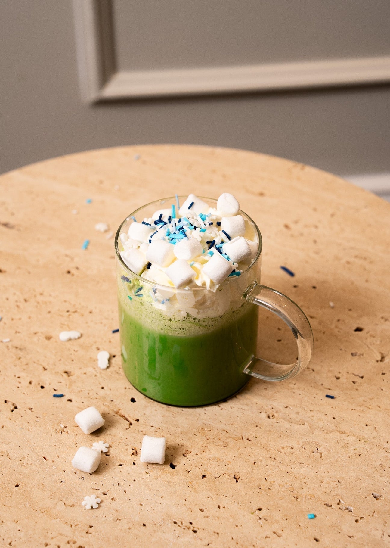 Ceremonial grade matcha latte in glass mug with whipped cream, marshmallows, and blue sprinkles